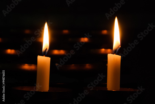 Two burning candles on a dark background