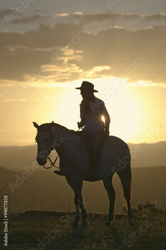 Female horseback rider and horse ride to overlook at Lewa Wildlife Conservancy in North Kenya  Africa at sunset