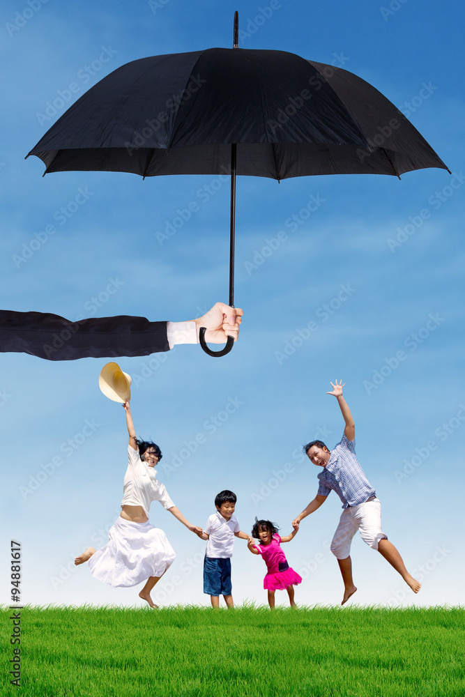 Attractive family jumping at field under umbrella