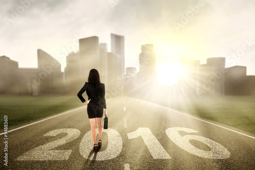 Female worker walking on the road with numbers 2016