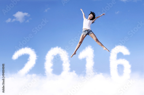 Joyful woman jumping on the cloud with numbers 2016
