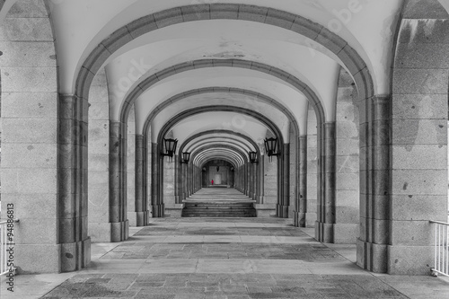 Symmetrical corridor with rows of columns. Black and white photo.