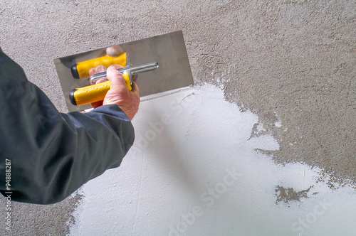Construction worker - plastering and smoothing concrete wall wit photo