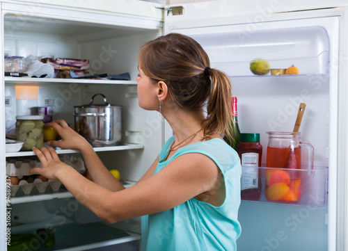 Woman near full fridge.