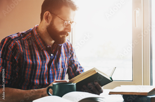 concentrated bearded man reading book