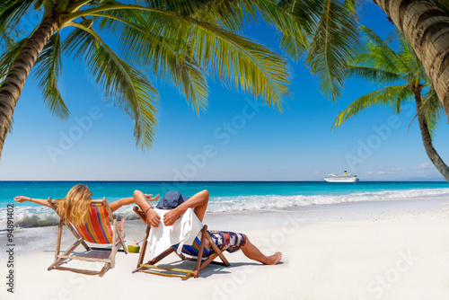 Couple on a tropical beach in the Maldives with cruise ship passing by