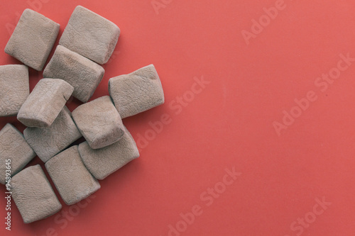 Pile of chocolate marshmallows in red pastel background.