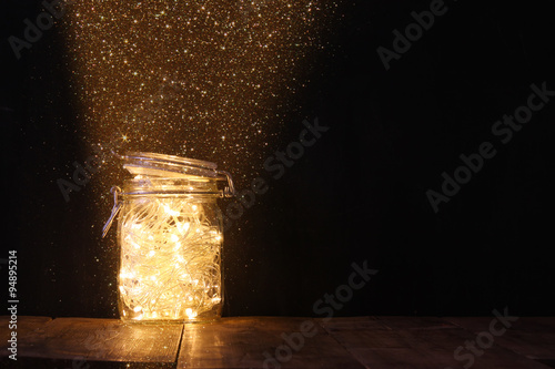 low key and vintage filtered image of fairy lights in mason jar with. selective focus.
 photo