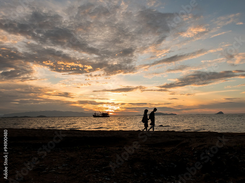 Silhouette couple of lover walking along the sea beach with silh