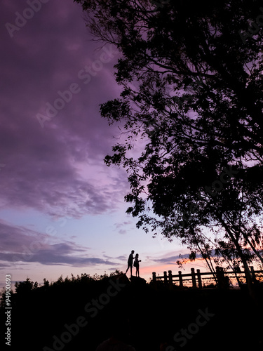 Silhouette Couple of lover standing on the rock top when twiligh