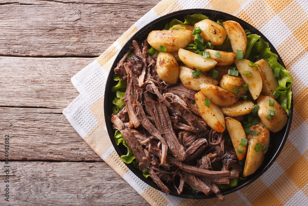 Pulled pork and fried potatoes on a plate horizontal top view
Pulled pork and fried potatoes on a plate horizontal top view