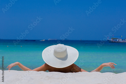 Fototapeta Naklejka Na Ścianę i Meble -  Woman in white hat lying on the beach, blue sea and sky background