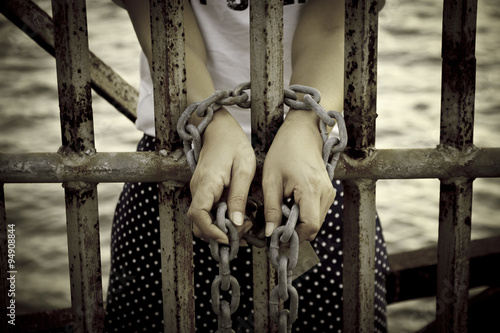 Stock Photo:.Rusty chains, shackles binding the hands of a prett photo