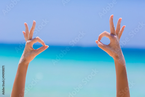 Female hands showing ok sign on blue sea background