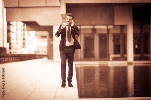 Photos Portrait of a businessman phoning and drinking coffee.