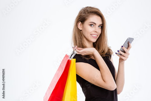 Woman holding shopping bags and using smartphone