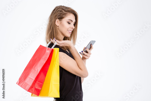 Woman holding shopping bags and using smartphone