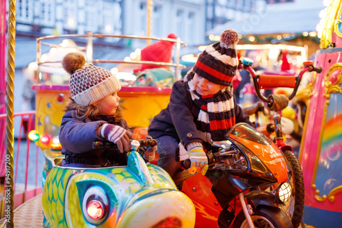 Little boy and girl on a carousel at Christmas market
