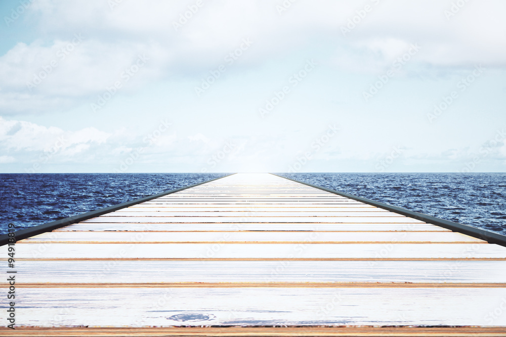 Wooden pier in the water with light sky