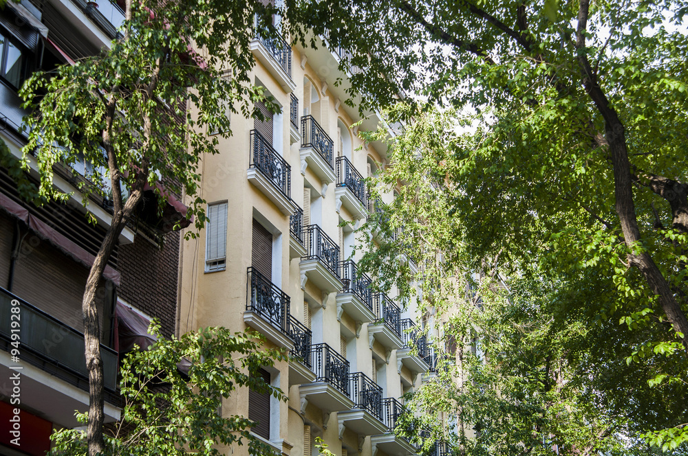 Obraz premium Architecture in Madrid. Trees and buildings sharing spaces in Madrid, Spain.