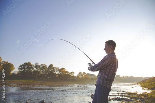 the fisherman is fishing on a river in the early morning.