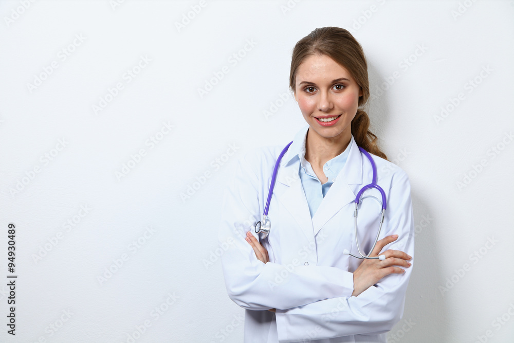 Friendly smiling young female doctor, standing near wall Friendly smiling young female doctor, standing near wall