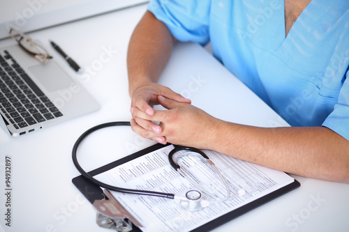 Portrait of unknown male surgeon doctor sitting at the table in hospital office, stethoscope