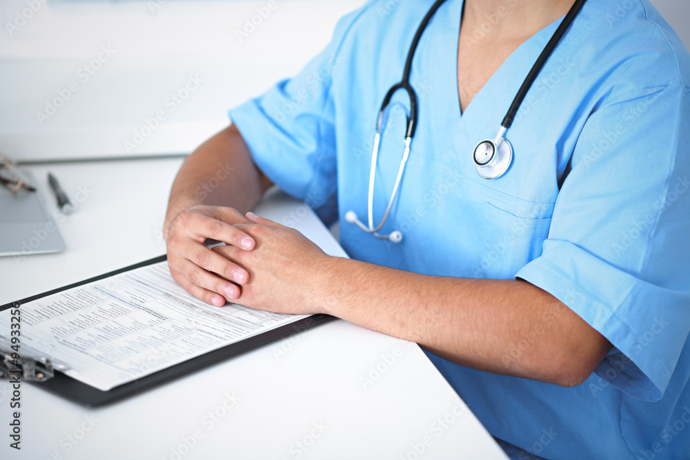 Portrait of unknown male surgeon doctor sitting at the table in hospital office, stethoscope