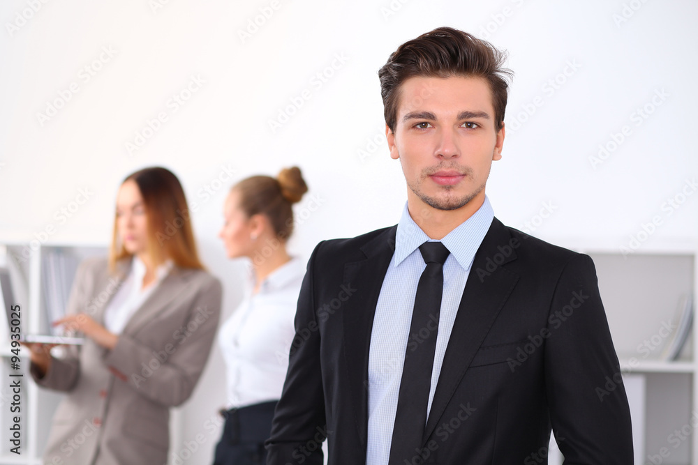 Cheerful business man in office with colleagues in the background, sturt up team Cheerful business man in office with colleagues in the background, sturt up team