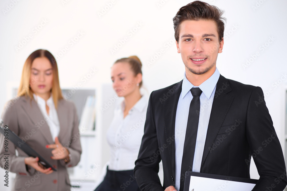 Cheerful business man in office with colleagues in the background, sturt up team Cheerful business man in office with colleagues in the background, sturt up team