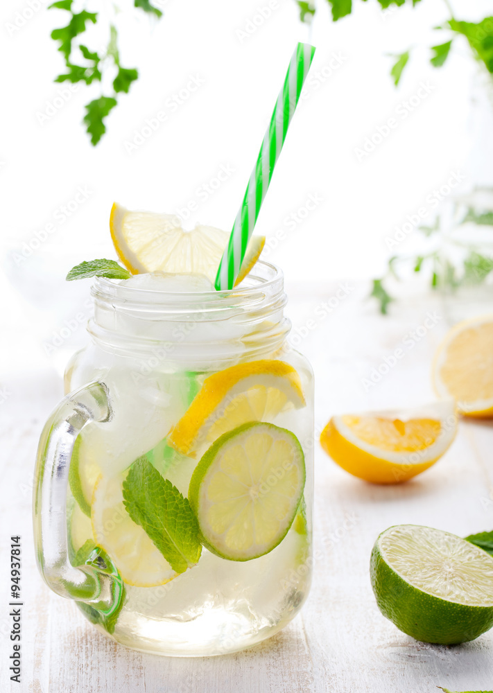 Fototapeta premium Lemonade with ice, lemon and lime slices in jar, straw.