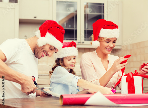 smiling family in santa helper hats with gift box
