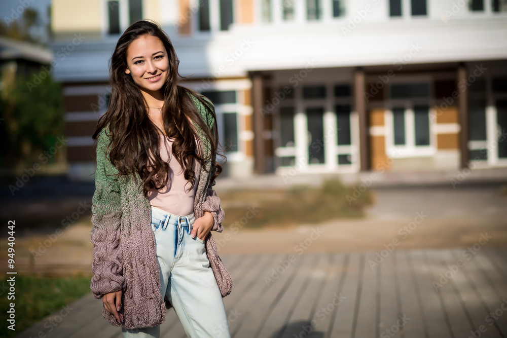 Fototapeta premium Beautiful young brunette girl walking down the street