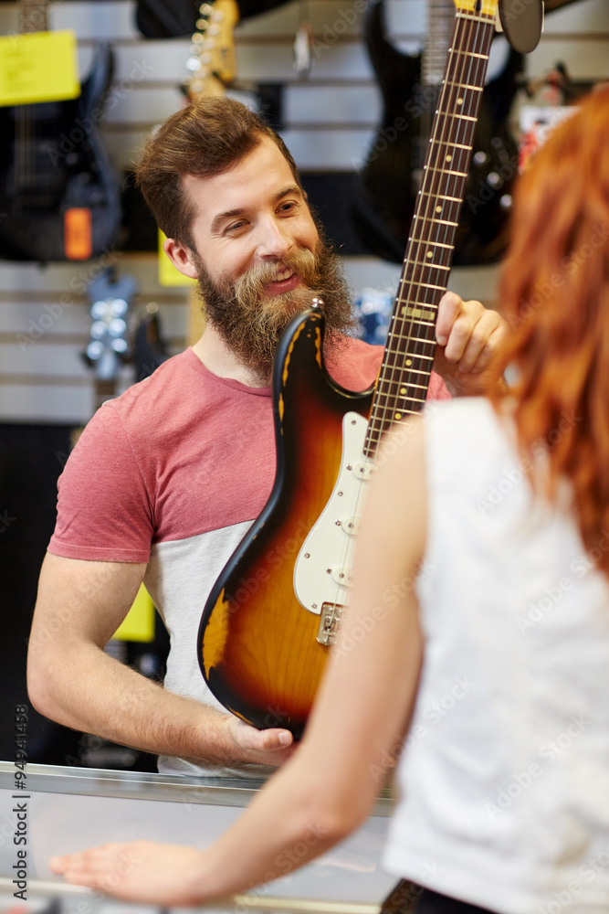 Fotografija assistant showing customer guitar at music store