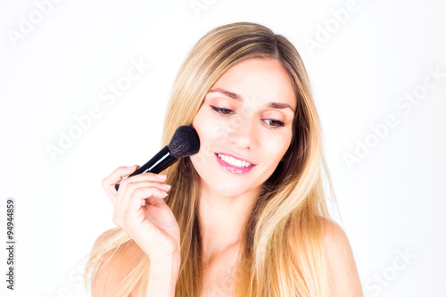 young woman with smile with teeth apply blush on face with large brush