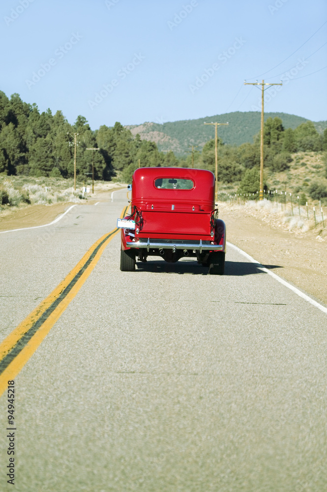 A restored bright Red Roadster hotrod pickup truck, mid-30's, drives rural highway in Kern County near Lockwood Valley, CA