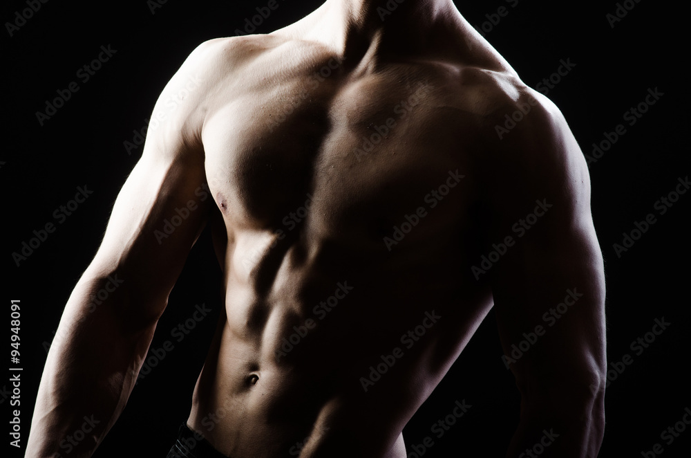 Muscular man posing in dark studio Muscular man posing in dark studio