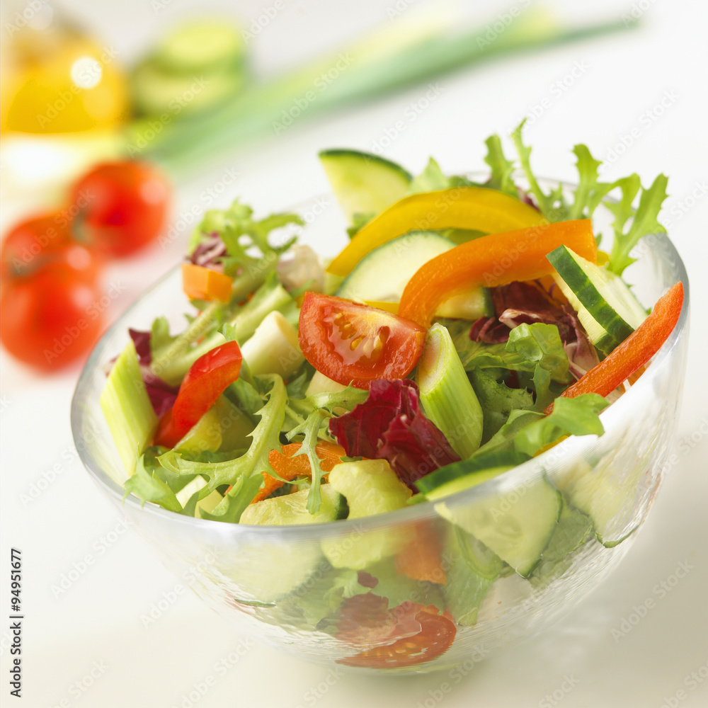 Bowl of fresh mixed salad with ingredients behind. Bowl of fresh mixed salad with ingredients behind.