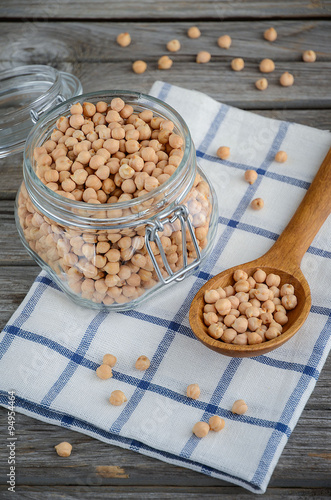 Raw dry chickpeas in a glass jar on the wooden table