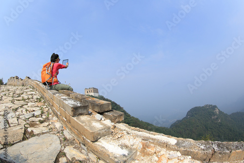 young woman hiker use digital tablet sit on chinese great wall