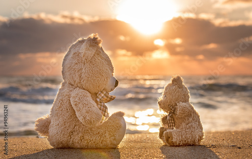 Teddy bears sitting on the beautiful beach with love. Concept ab photo