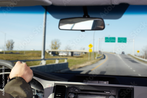 Hand of man driving on a highway.