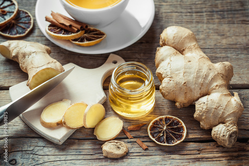 Sliced ginger root on cutting board, jar of honey and tea cup on