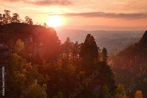 Autumn sunset in rocks. View over sandstone rocks to fall colorful valley of Bohemian Switzerland.