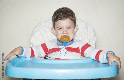 Niño sentado en la silla de comer photo