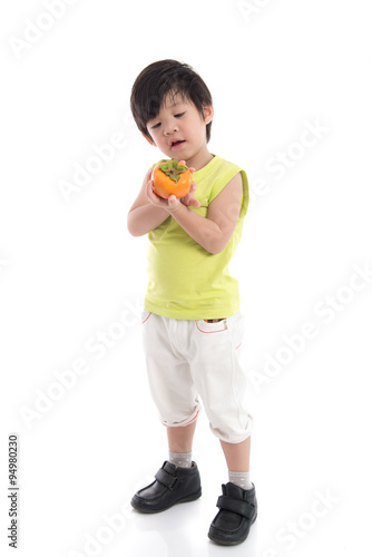 Cute asian boy holding persimmon