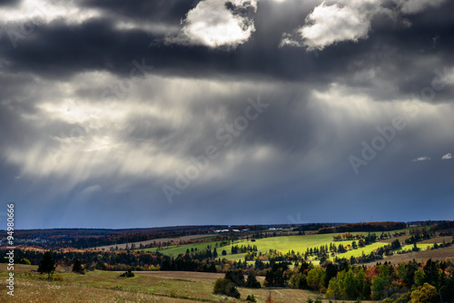 Light leaking though the dark clouds illuminating a small field.
