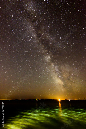 Milky Way shot across a bay with lights reflecting off the water