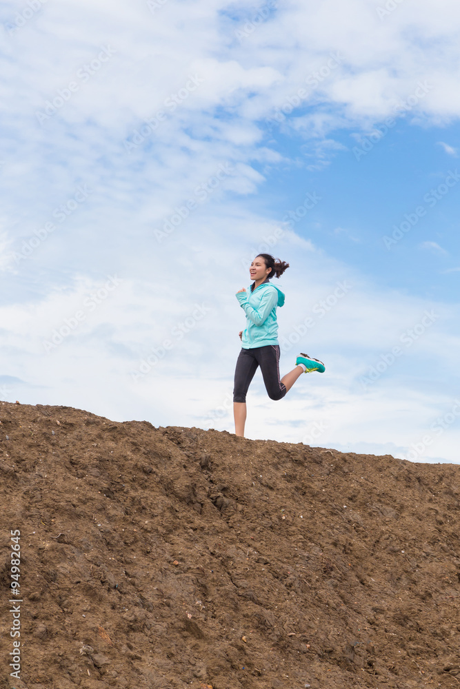 young woman running on trail with blue sky background young woman running on trail with blue sky background