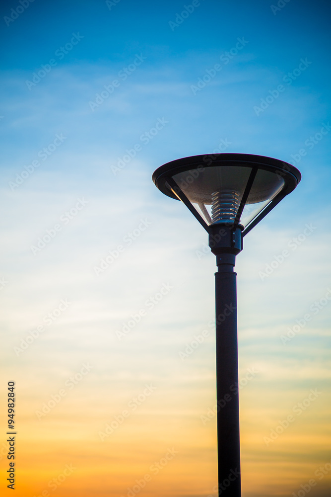 Street lamp, lamppost with lights on during daytime with backgro